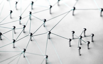 Abstract network made of metal pins connected with strings on a white background.